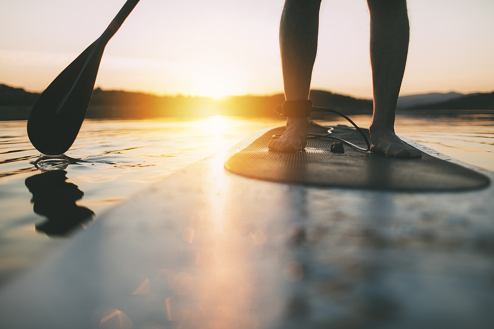 Eine Person auf eine SUP die im Sonnenuntergang paddelt