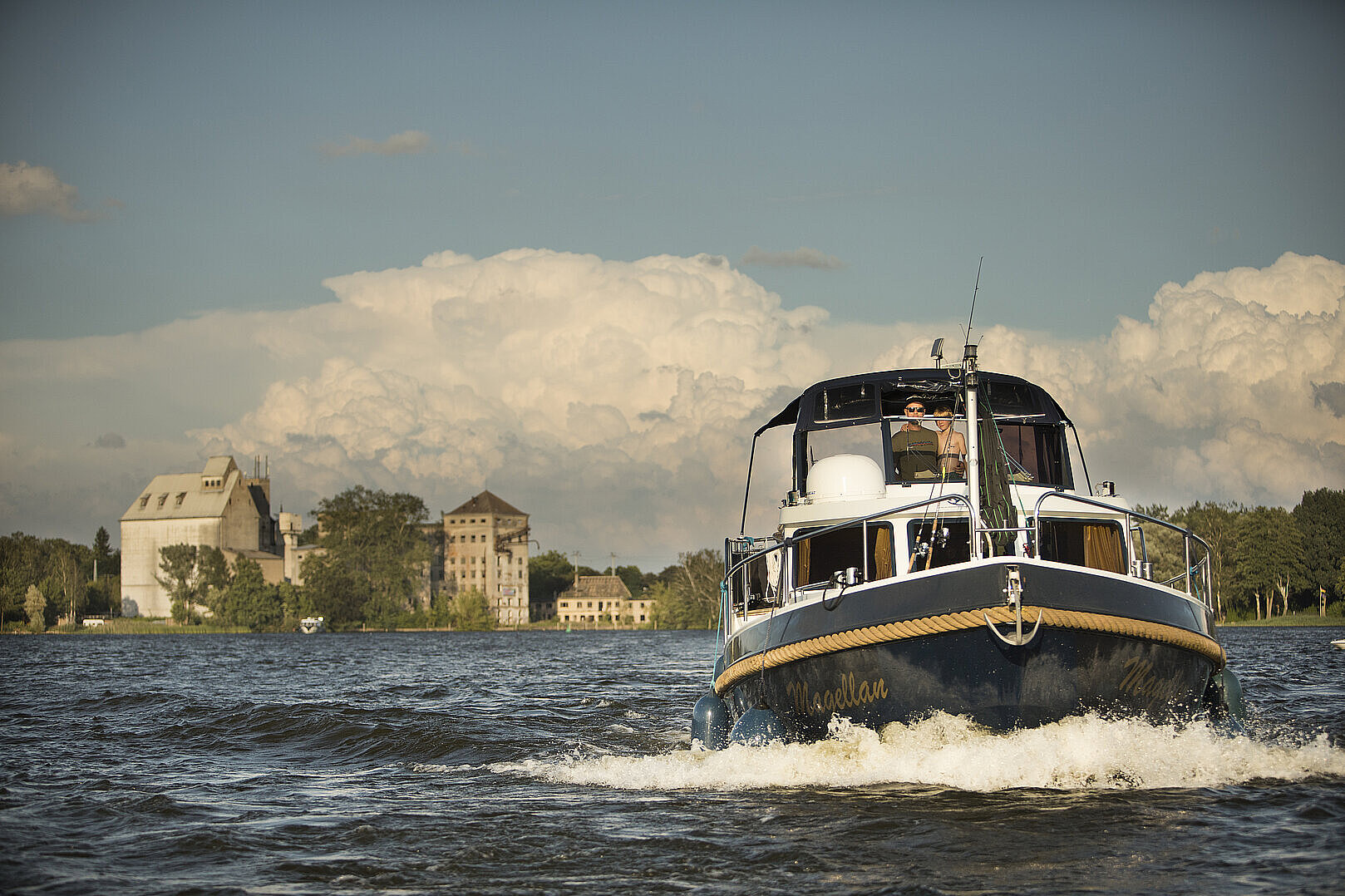 Das Bild zeigt ein junges Paar unterwegs mit einer Yacht in einem Kanal.