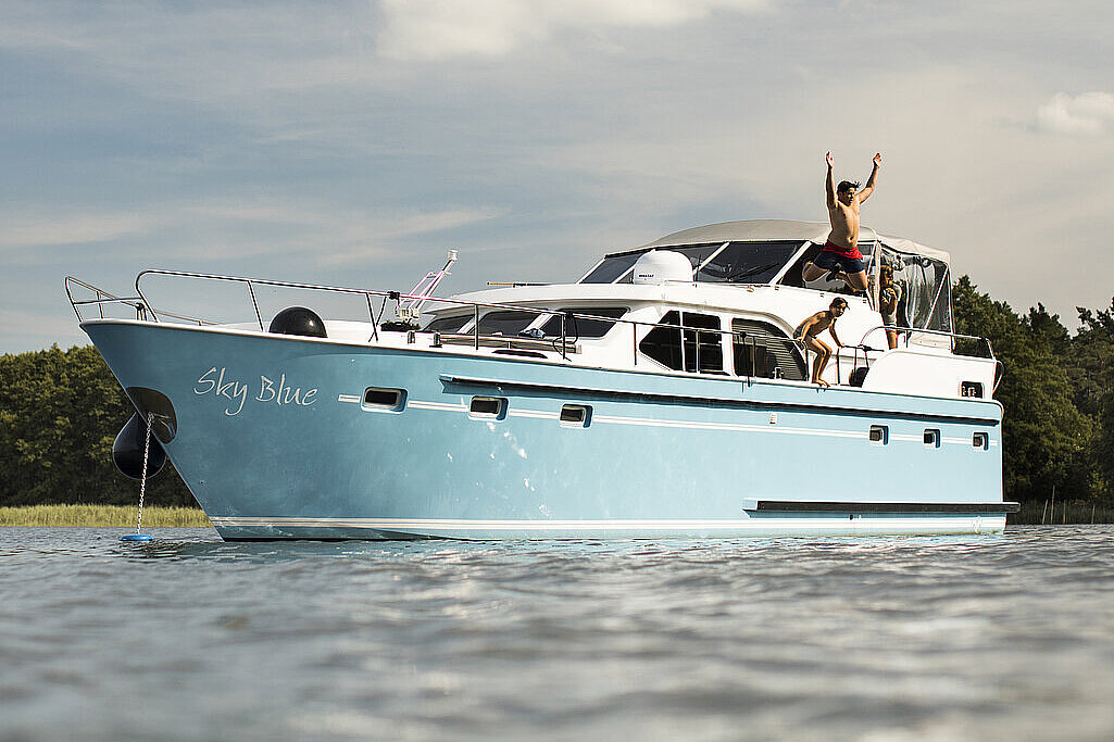 Personen springen von einer Yacht aus ins Wasser