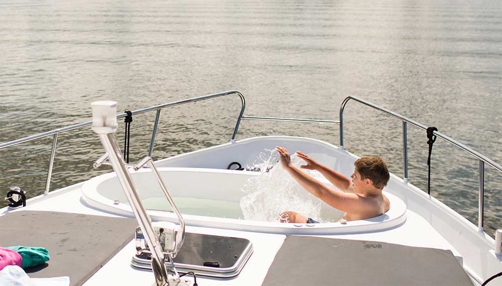 Ein Junge sitzt in einem Pool am Bug auf einer Yacht.